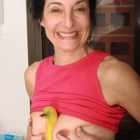 Mature lady strips nude in the kitchen before taking a banana to her wooly cootchie